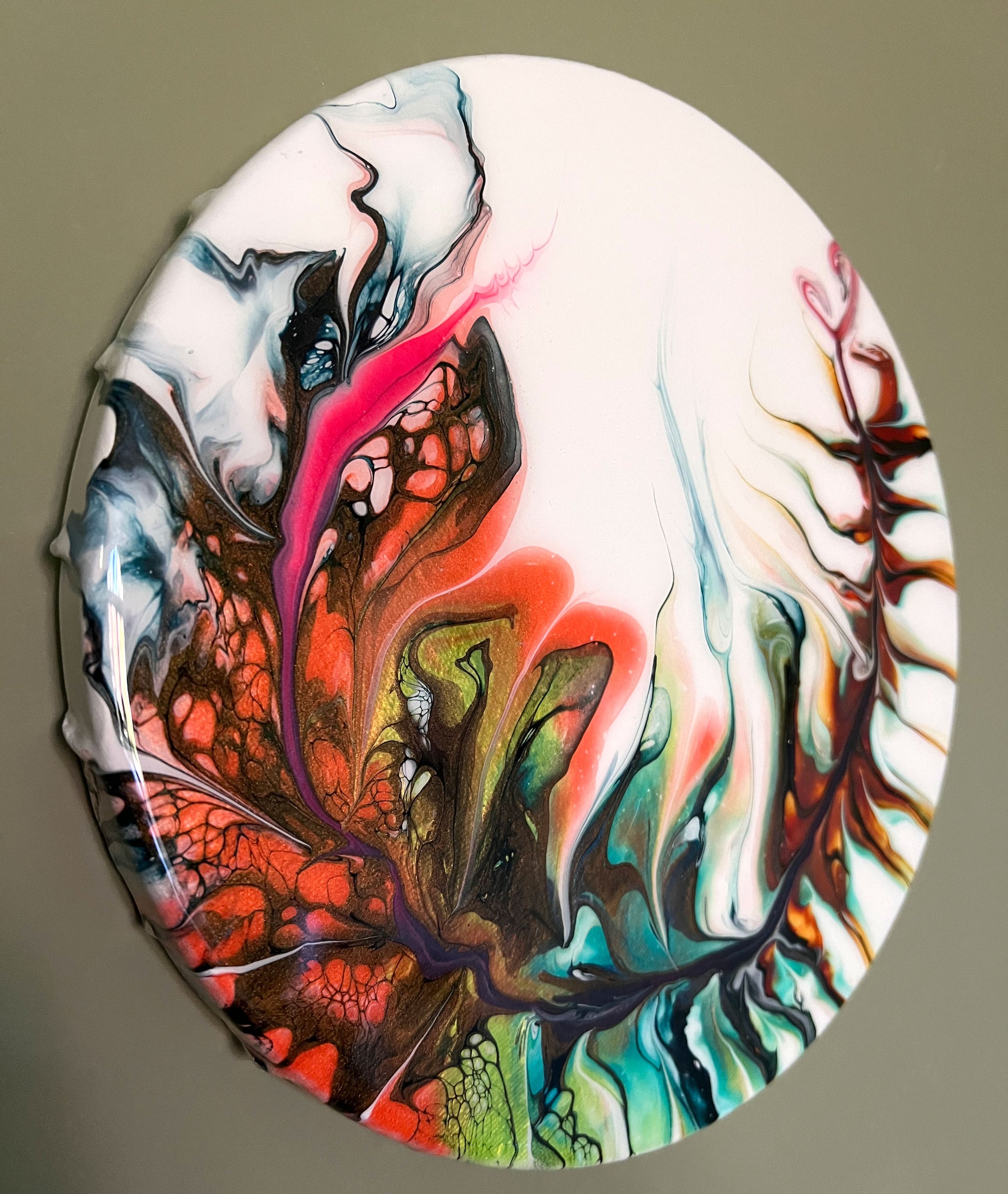 side image of a 9 inch round canvas with a hand painted feather in multiple iridescent colors